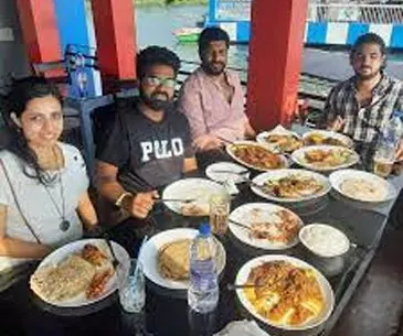 Guests enjoying a seafood meal at a floating restaurant in Poovar
