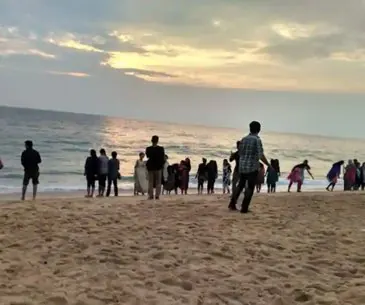 Visitors on Poovar golden sand beach at the river estuary